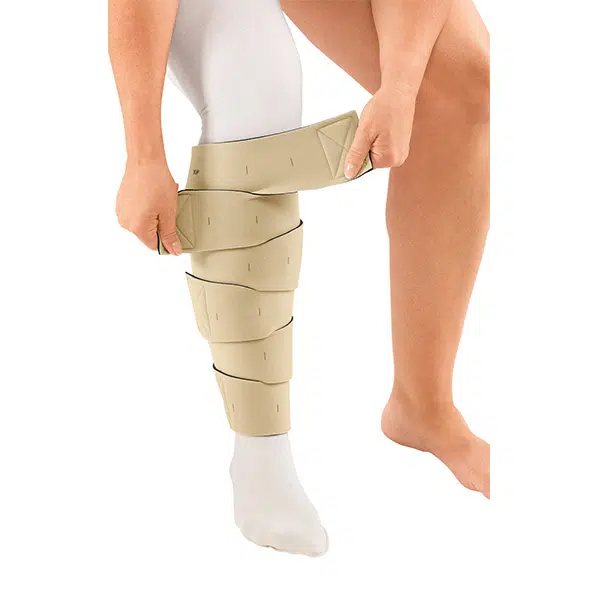 Patient fastening a circaid reduction kit wrap around the lower leg