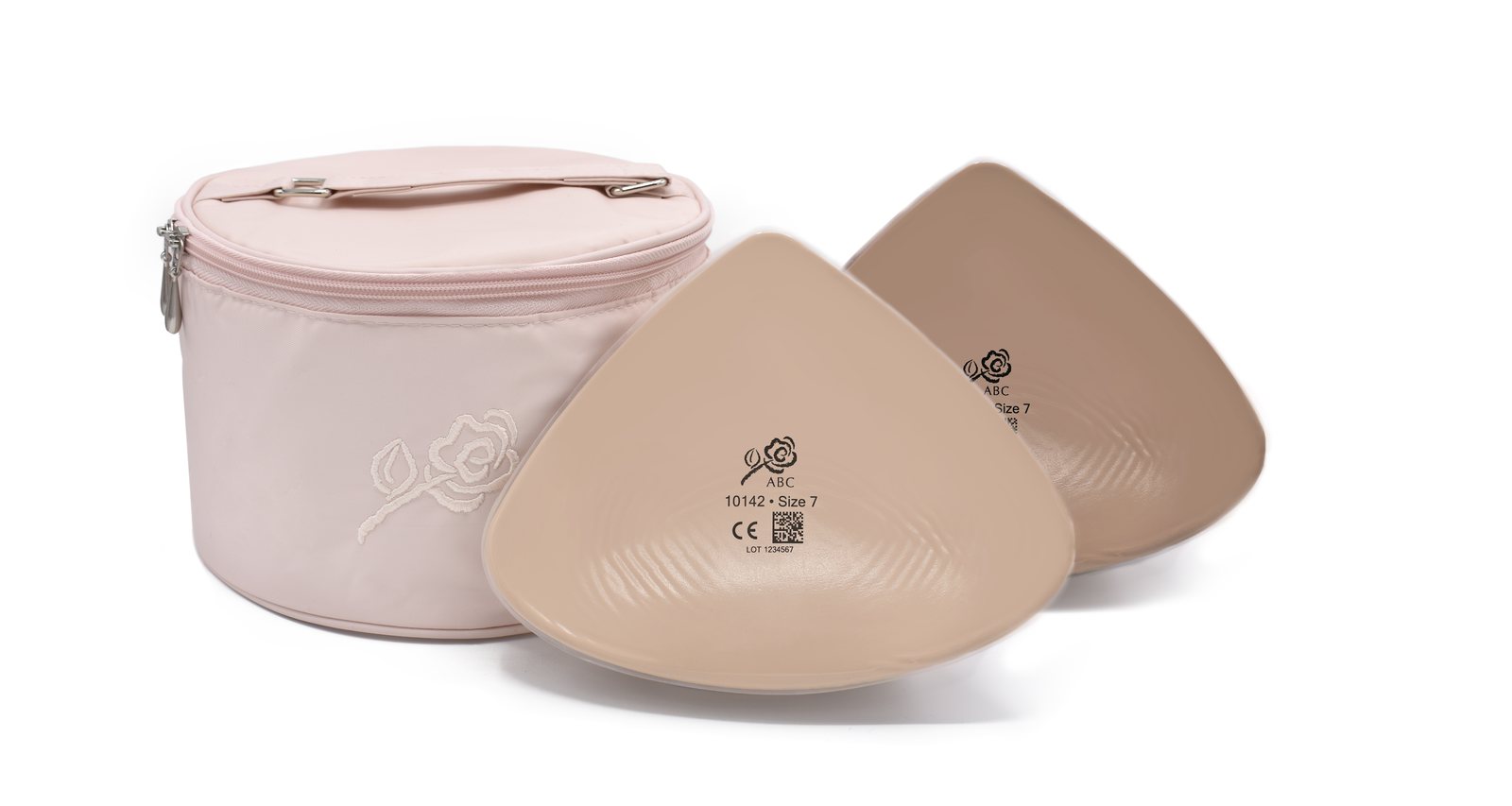 ABC triangle silicone breast forms in two skin tones beside a pink rose-embroidered carry case